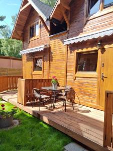 una terraza de madera con mesa y sillas frente a una casa en Domki Pod Dębami, en Pobierowo