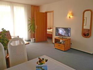 a living room with a television and a table with flowers at Haus Seeschwalbe Ferienwohnungen in Göhren