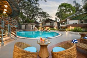 a swimming pool with wicker chairs and a table at Arova Woods Zinc Journey by The Fern, Lonavala in Lonavala