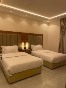 アル・マジュマアにあるالجنى للشقق المخدومةのベッド2台(サイドサイドサイド)が備わるホテルルーム内のベッド2台