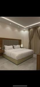 um quarto com uma grande cama branca num quarto em الجنى للشقق المخدومة em Al Majmaah