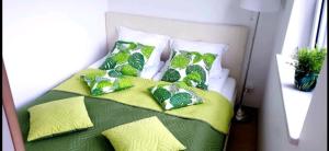 a bed with green and white pillows on it at Apartament Gdańsk Śródmieście Tartaczna 42 in Gdańsk