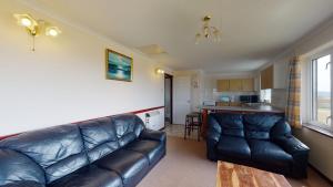 een woonkamer met een leren bank en een keuken bij D56 Beachcomber, Riviere Towans in Hayle