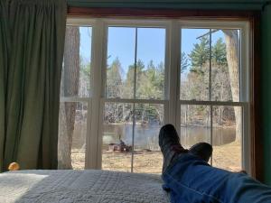 a person laying on a bed looking out a window at 2 bedroom-Riverfront-Fireplace - Pet ok in Pine City