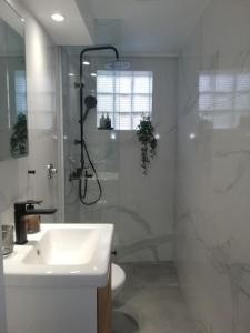 a white bathroom with a shower and a sink at BRIO luxurious urban stay in Heraklio,WiFi,ΑC in Heraklio