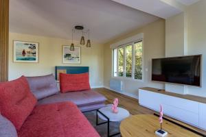 uma sala de estar com um sofá vermelho e uma televisão de ecrã plano em O'DUNE Pyla Plage -appartement jacuzzi vue mer - em Pyla Sur Mer