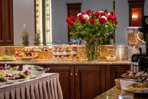 a buffet with red flowers and food on a counter at Hotel Gródek in Krakow