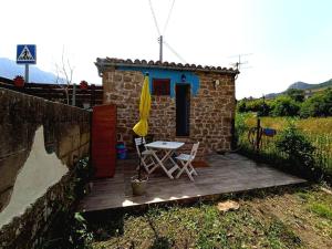 eine Terrasse mit einem Tisch und einem Sonnenschirm in der Unterkunft Cabaña de Piedra en Picos de Europa in Las Arenas