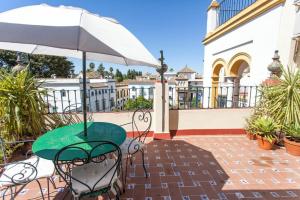 einen Tisch und Stühle mit Sonnenschirm auf dem Balkon in der Unterkunft Plaza de Santa Cruz in Sevilla