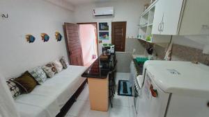 a living room with a couch and a kitchen with a refrigerator at Casinha guagiru in Trairi