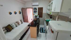 sala de estar con sofá y cocina con nevera. en Casinha Guajiru, en Trairi