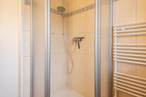 a shower in a bathroom with white tiles at Haus Heidehörn, App 5 in Wenningstedt +19 photos