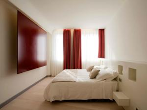 1 dormitorio con cama blanca y ventana en Eos Hotel, en Lecce