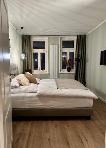 ein Schlafzimmer mit einem großen Bett und zwei Fenstern in der Unterkunft Ferienwohnung Rathausblick 2 in Blankenburg