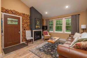 sala de estar con sofá de cuero y chimenea en Wilderness Meadows, en Pine City