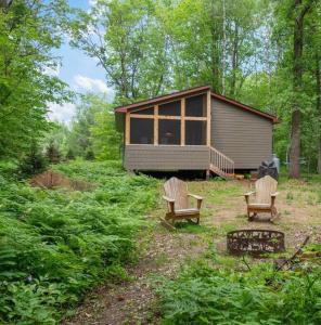 two chairs and a cabin in the woods at Wilderness Meadows in Pine City