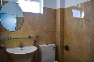 un bagno con lavandino, water e specchio di Catamaran6 Guest Inn a Trincomalee