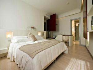 a white bedroom with a large bed and a kitchen at Eos Hotel in Lecce