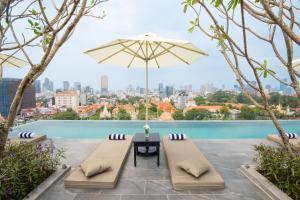 un patio con mesa, sillas y sombrilla en GLOW PARK HOTEL Grand Royal Palace, en Phnom Penh