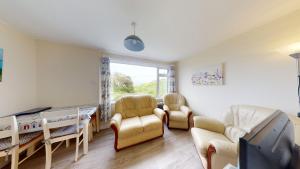a living room with chairs and a table and a tv at E17 Glenvale, Riviere Towans in Hayle
