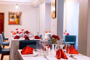 uma sala de jantar com mesas brancas e guardanapos vermelhos em Legend Boutique Hotel em Kigali