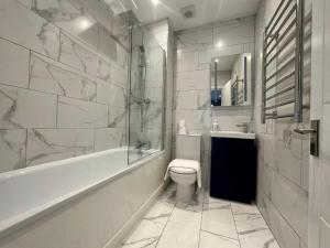 a bathroom with a tub and a toilet and a sink at King Size Bed Central Location Stylish Studio TMS in Brighton & Hove