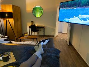 a person laying on a couch in front of a large tv at Wood-Appartement in Bielefeld