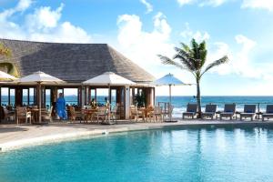 a swimming pool with tables and chairs and the ocean at Hotel Manapany in Gustavia