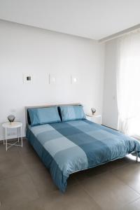 a bed in a white room with a blue bedspread at A CASA DI FIBI in Salerno