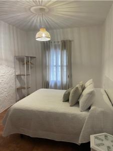 a bedroom with a large white bed with a chandelier at Casa Lucas in Grazalema