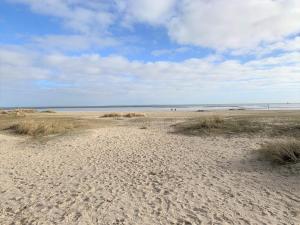 a sandy beach with grass and the ocean in the background at 50 3 N Nordkoje in Wangerland