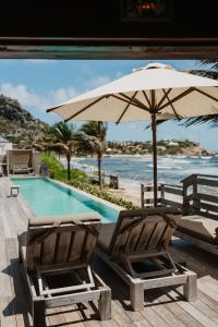 two chairs and an umbrella next to a swimming pool at Hotel Manapany in Gustavia