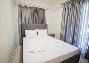 a bedroom with a bed with white sheets and curtains at Xelidonia Apartments by RentalsPro - Nikiti Halkidiki in Metamorfosi