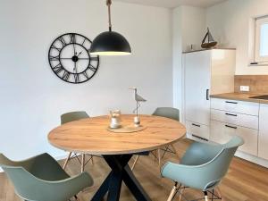 a dining room table with chairs and a clock on the wall at 49 5 M Ankerplatz in Wangerland