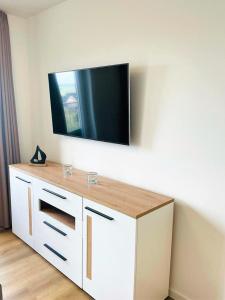 a white cabinet with a television on a wall at 49 5 M Ankerplatz in Wangerland