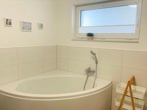 a white bath tub in a bathroom with a window at 49 5 M Ankerplatz in Wangerland