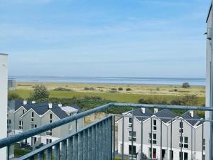 a balcony with a view of houses and the ocean at 49 5 M Ankerplatz in Wangerland