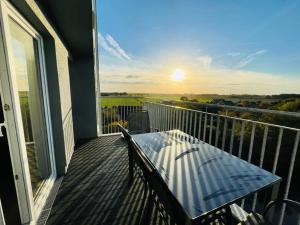 a balcony with a table and a view of the sunset at 49 5 M Ankerplatz in Wangerland +4 photos