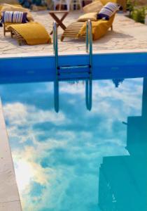 una piscina con sillas y el reflejo del cielo en el agua en MiaBella Resort, en Drage