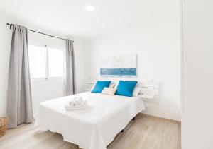 a white bedroom with a large bed with blue pillows at Moderno apartamento urbano en barrio histórico 3ºD in Santa Cruz de Tenerife