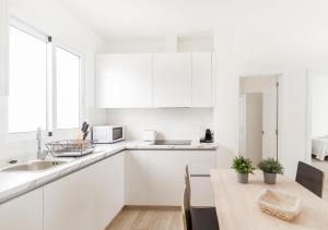 a white kitchen with white cabinets and a table at Moderno apartamento urbano en barrio histórico 3ºD in Santa Cruz de Tenerife