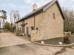 an old brick building with a road in front of it at Grange Cottages in Alnwick