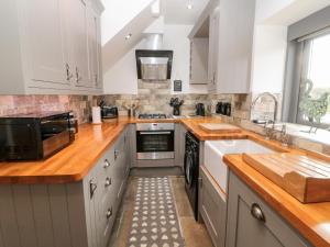 a kitchen with white cabinets and a sink at Grange Cottages in Alnwick