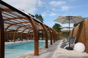 - une piscine bordée de chaises et d'un parasol dans l'établissement Volcans Vacances Les Chalets Du Lac, à Aydat