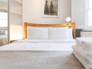 a bedroom with a bed with white sheets and a mirror at Roof Terrace Flat in Hampstead Pass The Keys in London