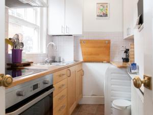 a kitchen with white cabinets and a sink and a dishwasher at Roof Terrace Flat in Hampstead Pass The Keys in London