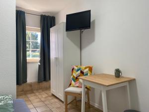 Hotel am See في Kreuzau: غرفة صغيرة مع طاولة وتلفزيون على الحائط