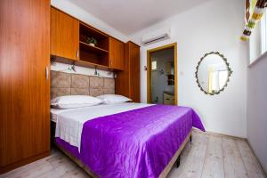 a bedroom with a purple bed and a mirror at Apartments Nino in Podstrana