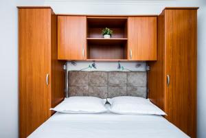 - une chambre avec un lit et des placards en bois dans l'établissement Apartments Nino, à Podstrana