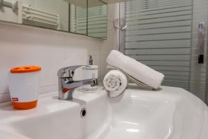 La salle de bains est pourvue d'un lavabo, d'un robinet et de serviettes en papier. dans l'établissement Apartments Nino, à Podstrana